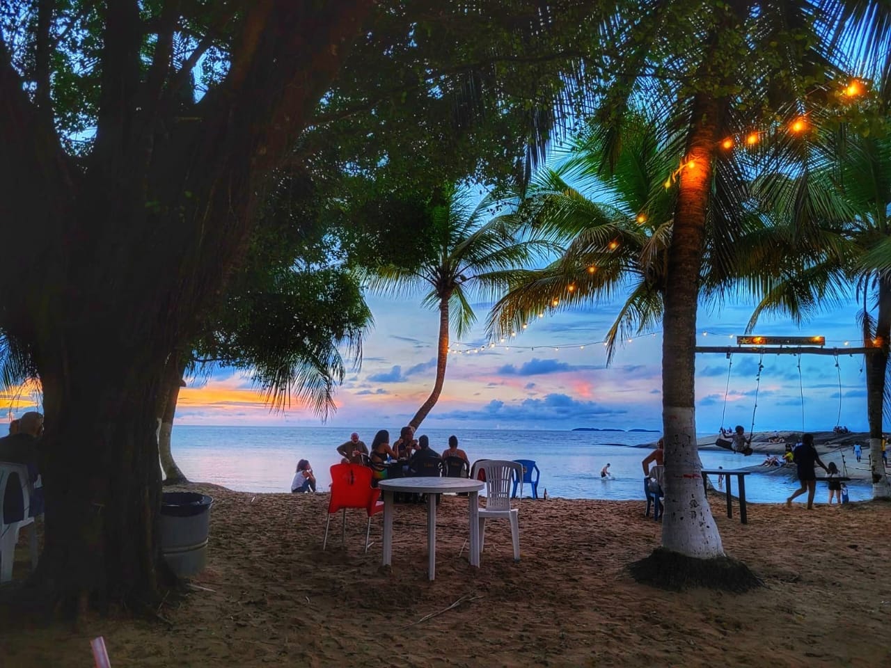 Coucher de soleil sur la plage du Copacabana, Kourou, avec guirlandes lumineuses entre les cocotiers